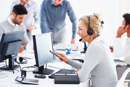 Woman in a call center setting with colleagues in the background ( USA Cabinets Outlet )