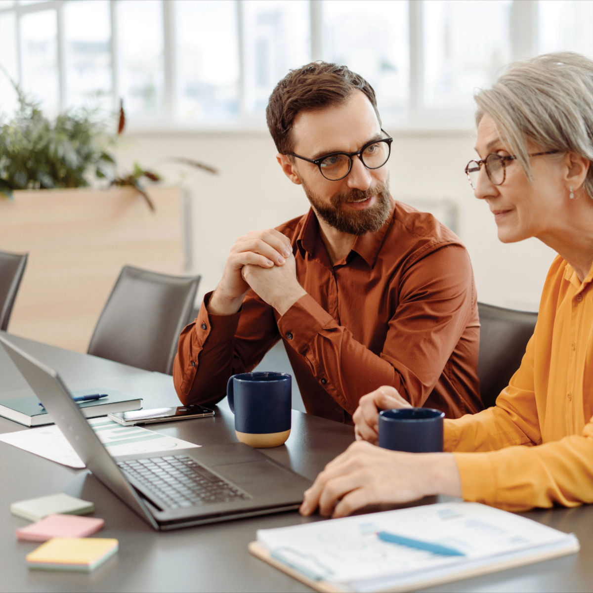 Two people sitting at a table with a laptop, discussing something ( USA Cabinets Outlet )