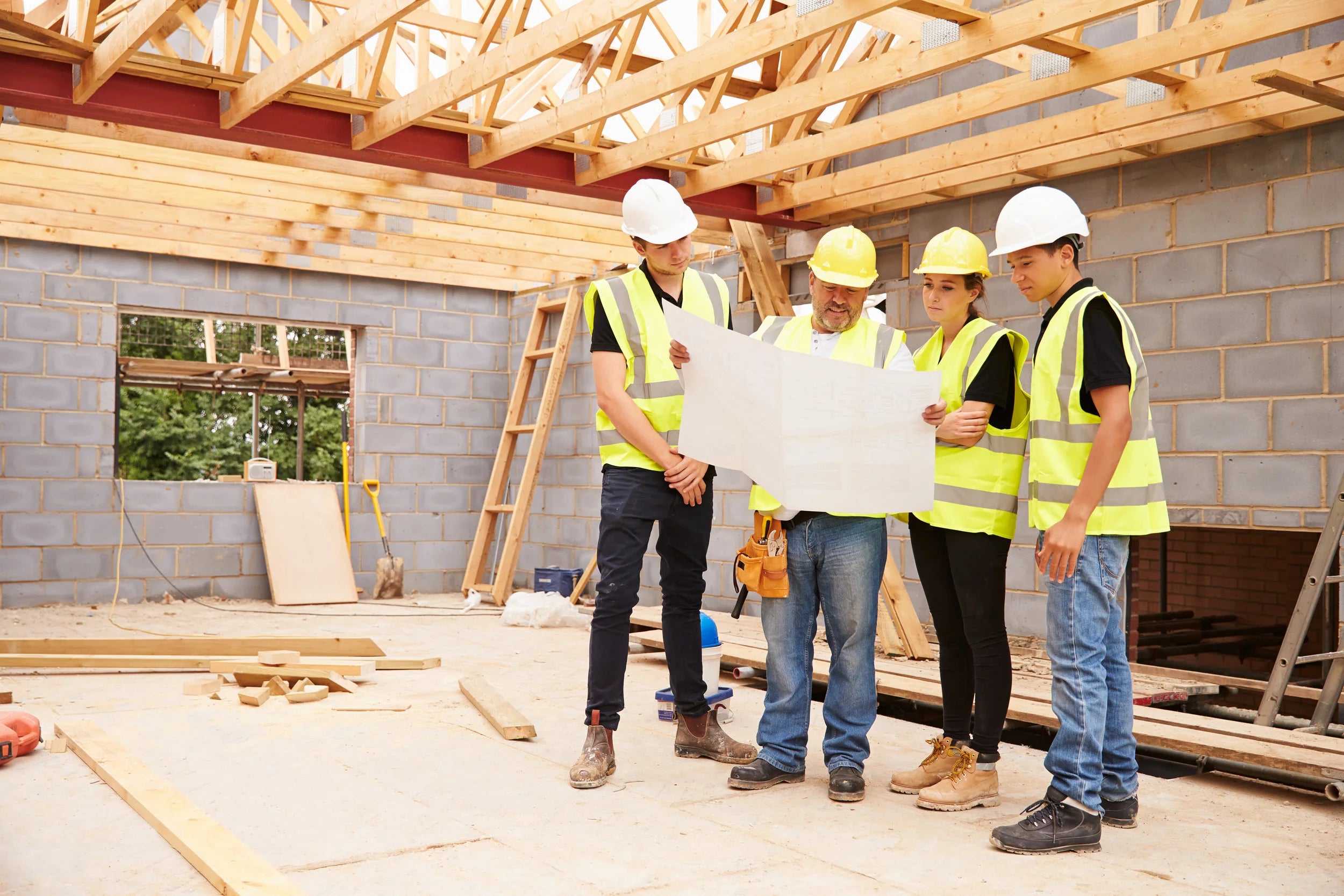 Group of construction workers in a building under construction holding blueprints ( USA Cabinets Outlet )
