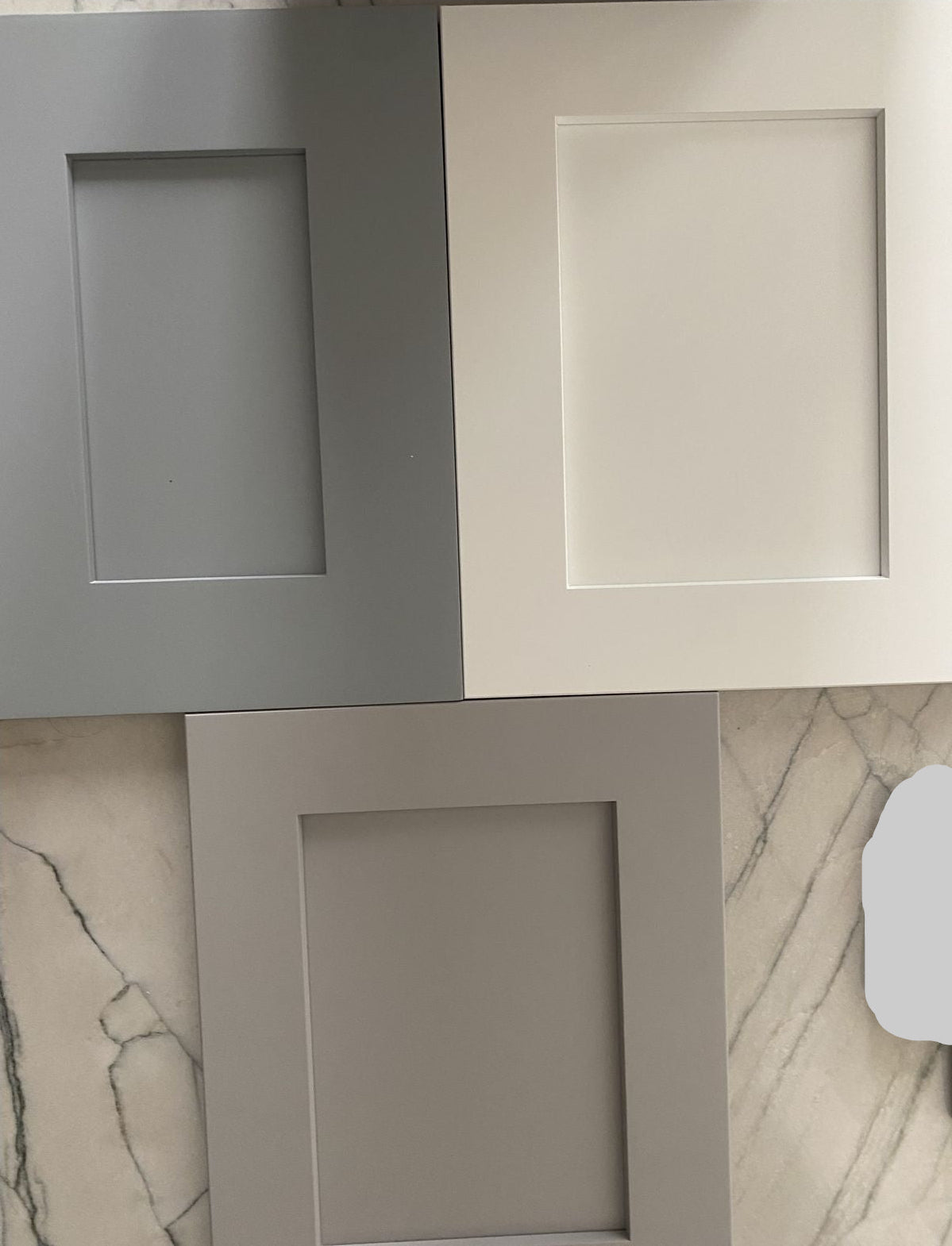 Three gray picture frames on a marble surface with a remote control.