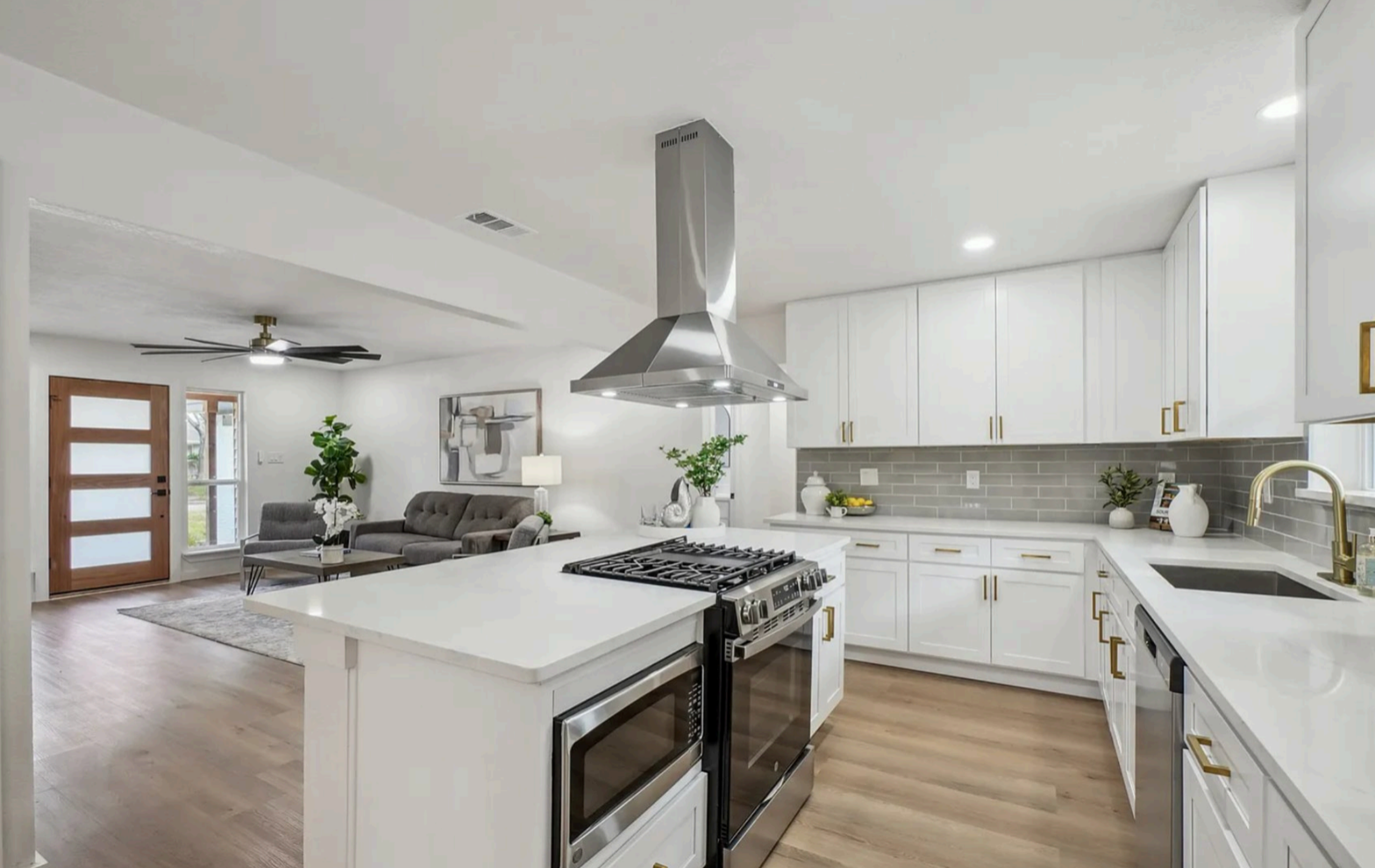 Modern kitchen with white cabinets, stainless steel appliances, and a view into the living room ( USA Cabinets Outlet ) 
