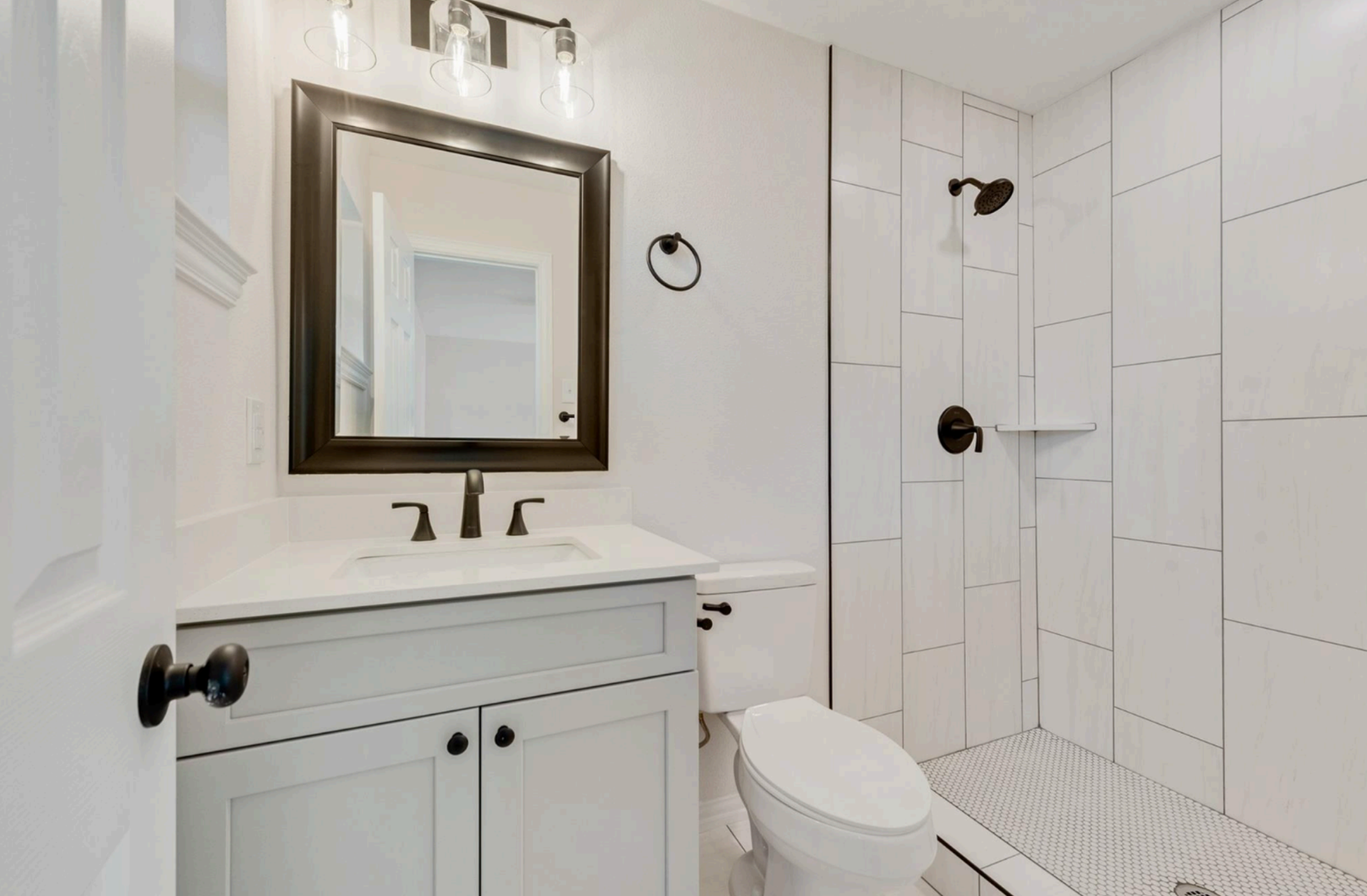 Bathroom with white vanity, mirror, toilet, and shower stall ( USA Cabinets Outlet )