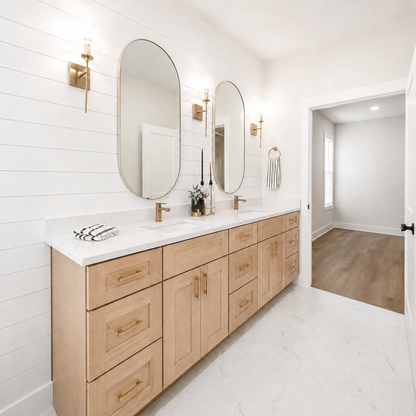 A modern double bathroom vanity with light oak wood cabinets, white marble countertops, two large oval mirrors, and gold wall sconces in a bright white shiplap bathroom.|USA Cabinets Outlet |