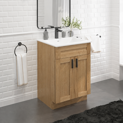 A single-basin bathroom vanity cabinet in a light oak wood finish with a white ceramic sink and a black faucet, shown in a modern bathroom setting with white subway tile walls, gray flooring, and a black towel rack.|USA Cabinets Outlet |